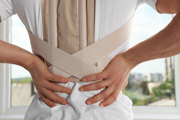 Closeup of man with orthopedic corset indoors, back view