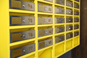 Many closed metal mailboxes with keyholes and numbers in post office, closeup