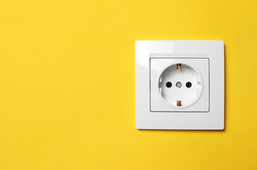 Power socket on yellow wall, space for text. Electrical supply