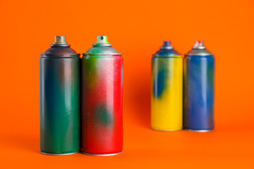 Used cans of spray paints on orange background