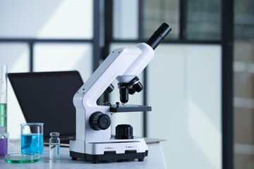 Modern microscope with glass slide on white table in laboratory, space for text