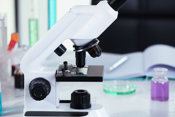Modern microscope with glass slide on white table in laboratory, closeup. Space for text