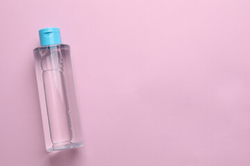 Micellar water on pink background, top view. Space for text