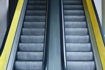 View on empty parallel escalators with yellow balustrades