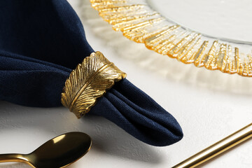 Dark blue fabric napkin and decorative ring for table setting on plate, closeup