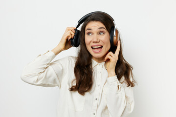 portrait of a beautiful happy woman with long dark hair happily listening to music with headphones on a light monochrome background for inserting an advertising layout