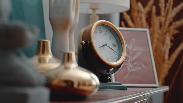 Desk clock near golden incense holders on bedside table