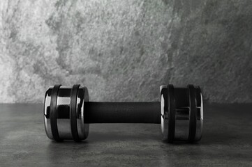 Metal dumbbell on table against grey background. Space for text