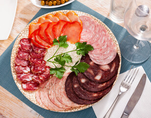 Delicious meat platter - sliced dry-cured pork loin, salami and blood sausage on serving plate with...