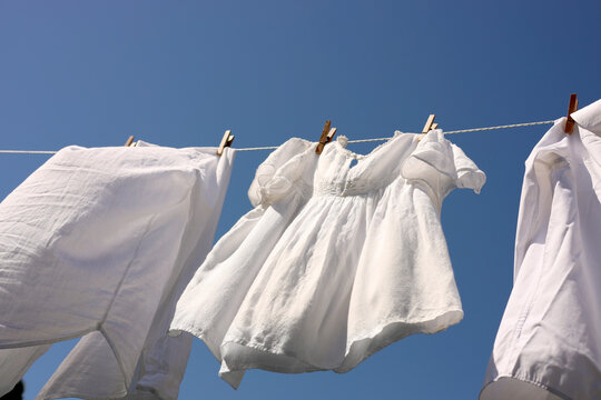 Clean clothes hanging on washing line against sky, low angle view. Drying laundry