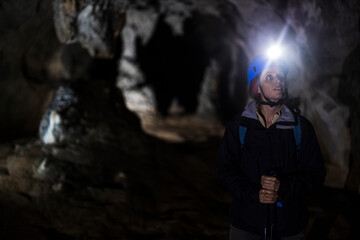 Fototapeta na wymiar Female Speleologist Admiring Scenic Cave Interior full of Stalactites and Stalagmites