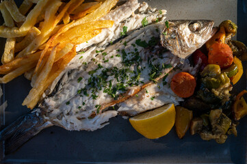 Grilled sea bass white fish served with potato chips and vegetables
