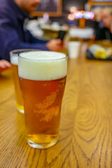Fresh draught lager or IPA beer is glass served in indoor cafe close up, pint of beer