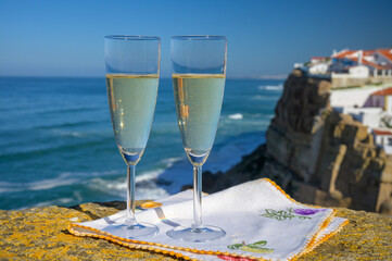 Glasses of champagne sparkling wine and view on white houses of picturesque village Azenhas do mar, Lisbon area, Portugal