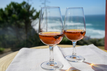 Tasting of sweet moscatel de setubal or porto portuguese wine and view on blue Atlantic ocean near Sintra in Lisbon area, Portugal