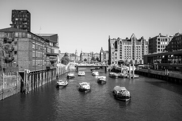 Gray-scale shot of boats in the river with building on the side in Hamburg, Germany