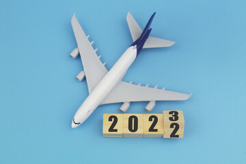 Airplane and wooden cubes with 2022 and 2023 on blue background. 