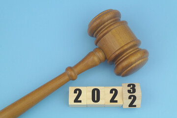 Wooden judge gavel and flipping numbers 2022 with 2023 on wooden cubes. Concept of changes in laws.