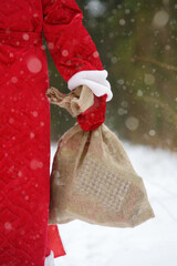 Santa Claus with bag of Christmas gifts is walking through snowy forest. Animator or parent in...