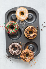 homemade donuts on a donut pan with assorted glazes and toppings. 