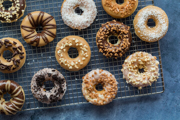 An above view of a cooling rack with glazed donuts and assorted toppings.