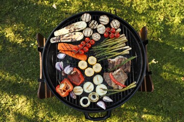 Delicious grilled vegetables and meat on barbecue grill outdoors, top view