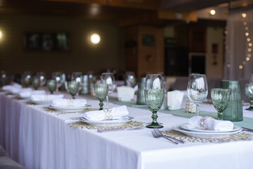 
Serving and decoration of the wedding table. Glasses, spoons, forks and white napkins