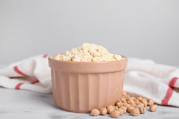 Chickpea flour in bowl and seeds on white marble table