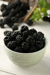 Bowl with fresh ripe blackberries on white wooden table