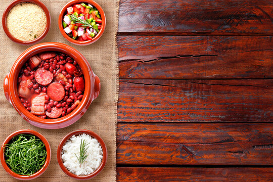 Brazilian feijoada, traditional food from Brazil cuisine, on ceramic casserole bowl, over rustic wooden table. Copy space