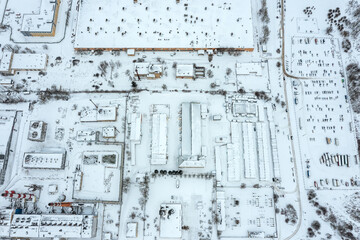 aerial top view of industrial district in winter. manufacturing buildings and warehouses covered with snow.