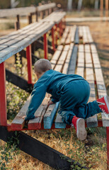 little boy climbs onto a bench on an autumn day in the park