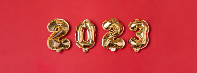 New year 2023 balloon. Gold foil helium balloon number 2023, party decoration on red background. Flat lay, merry christmas, happy holidays concept