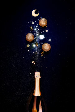 Bottle of champagne and golden shiny holiday decor, balloons on black background