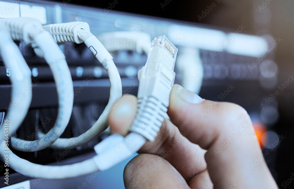Poster Hand on network cable in server room or data center for maintenance on server machine. Technology, connection and wires in datacenter, information storage and hands of engineer or technician closeup.