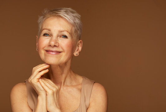 Beauty portrait of mature woman smiling with hand on face.