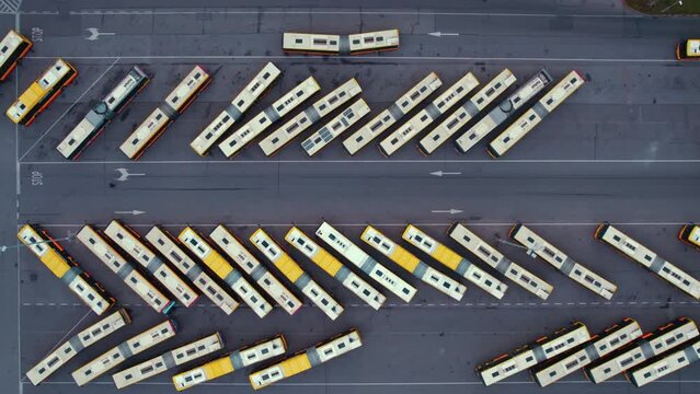 High angle slow motion drone shot of parked busses in the area of bus depot creating herringbone pattern. Modern transportation and public transport. High quality 4k footage