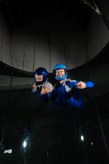 A man teaches a boy to fly in a wind tunnel. Lack of gravity.
