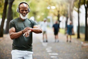 Music, time and running with a mature black man looking at his watch while out for a fitness run in...