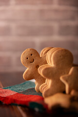 Homemade smiling gingerbread man cookie peeking out from a row of cookies. Standing out from crowd concept