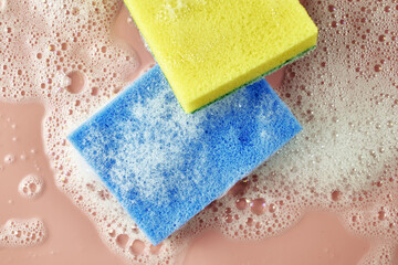 soap foam and two sponges on a pink background