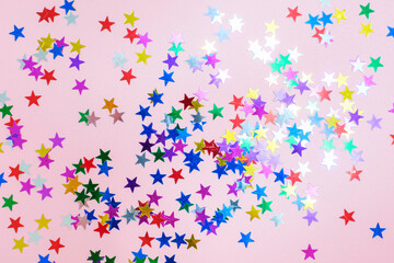 Fototapeta na wymiar Multicolored stars of confetti on pink background, top view