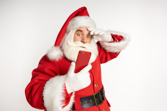 Surprised Santa in a headdress, suit, black belt, white gloves, getting ready to talk on the phone. Sale action, winter December. White background.