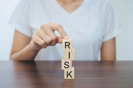 Businesswoman hand holding a wooden block. Typing the word risk. Risk hedging concept. elimination of risks.