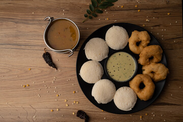 South Indian breakfast-Idli, sambar, wada, coconut chutney. Served in plate wooden background