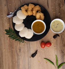 South Indian breakfast-Idli, sambar, wada, coconut chutney. Served in plate wooden background