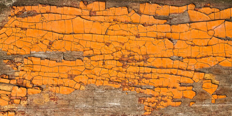 Peeling orange paint on an old wooden surface. Abstract background texture.