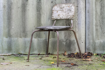 Old damaged stool against a slate background. Rusty vintage outdoor chair.