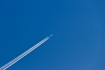 Airplane blowing smoke diagonally to blue sky