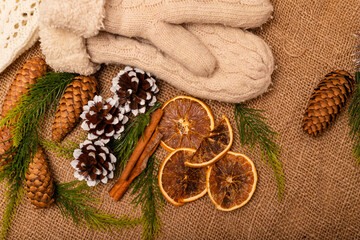 Obraz na płótnie Canvas Christmas composition. Christmas cones, mittens, cinnamon, oranges on burlap